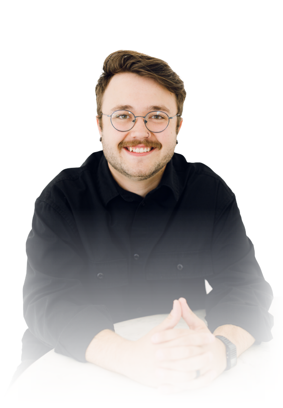 Smiling man in glasses and black shirt, seated against a white background.