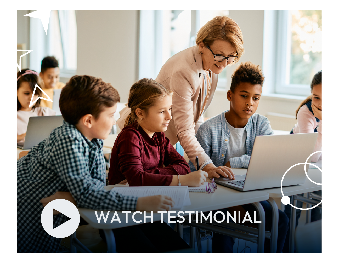 Teacher helping students use a laptop in a classroom with a “Watch testimonial” overlay