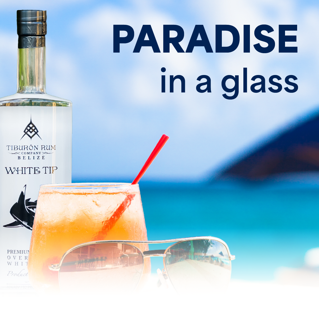 Rum cocktail by a beach with sunglasses and the text “PARADISE in a glass”