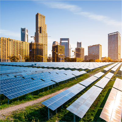 Solar panels in a field with a city skyline in the background at sunrise