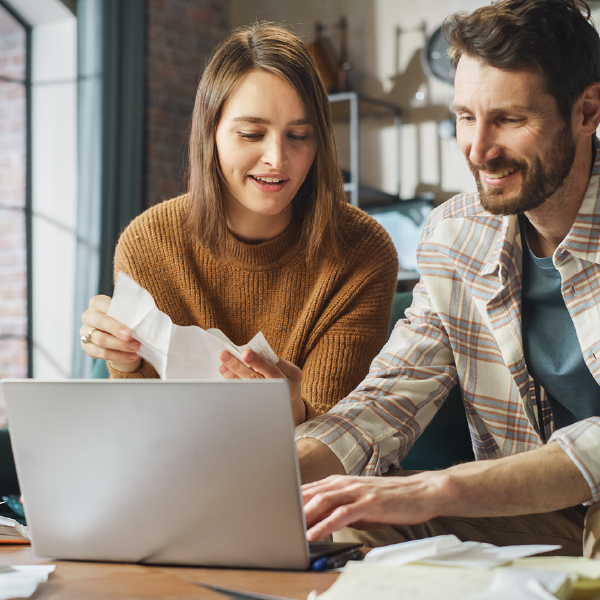 Two coworkers reviewing paperwork beside a laptop at a table