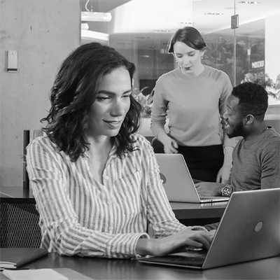 People working together in a modern office, with one person typing on a laptop in the foreground.