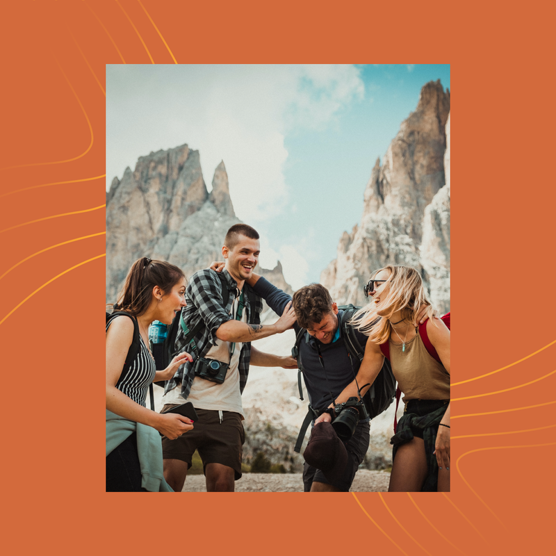 Friends hiking between rocky cliffs, smiling and leaning together in a mountain valley.