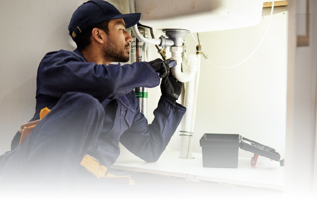 Technician using a drill to work on a wall-mounted fixture indoors