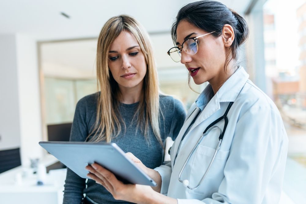 Two medical professionals reviewing a tablet in a bright clinic office
