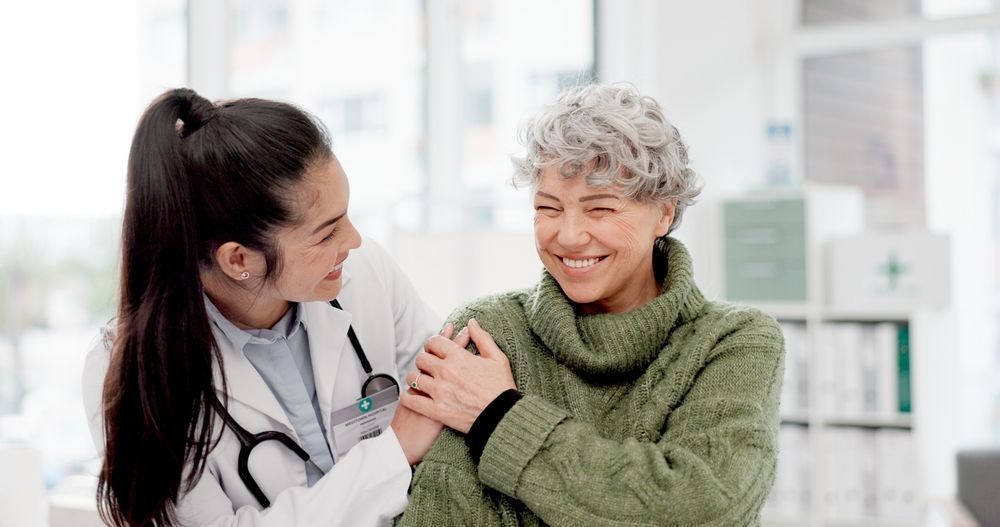 Doctor smiling and holding an elderly patient’s shoulder in a bright clinic