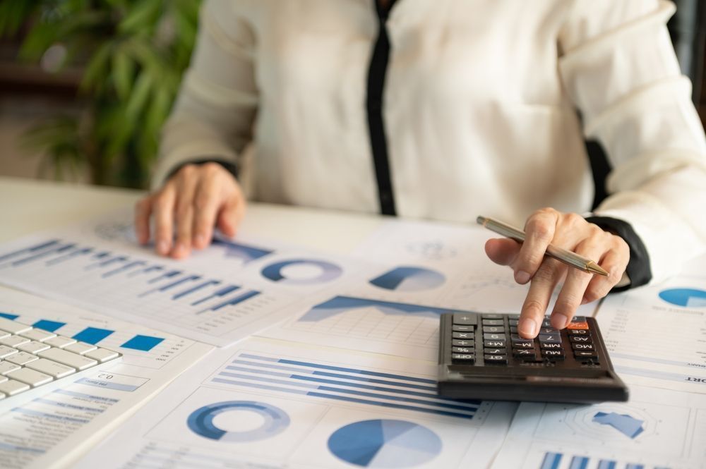 Person calculating financial charts with a calculator at a desk