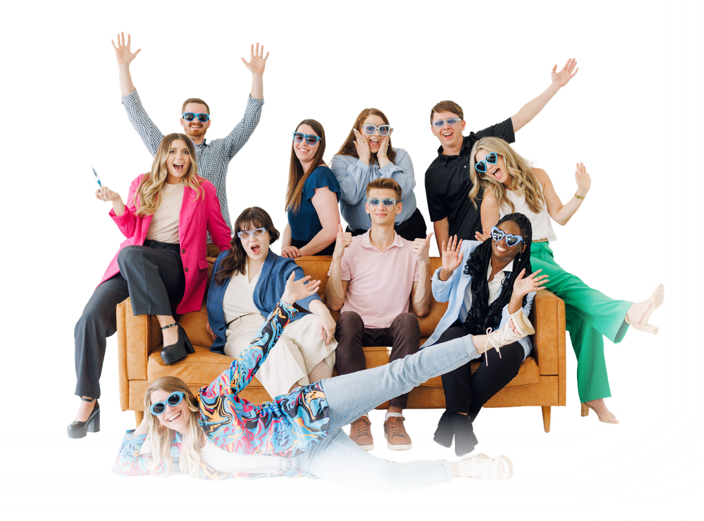 Group of people posing playfully on and around a brown couch against a white background