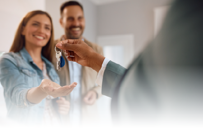Handing over house keys to a smiling couple in a bright office