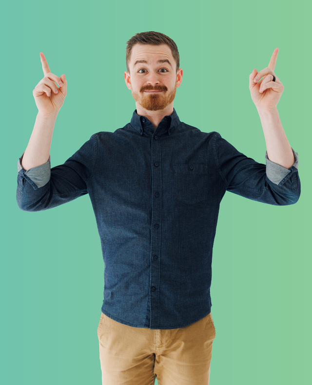Person standing against a green background, pointing upward with both index fingers and a slight smile