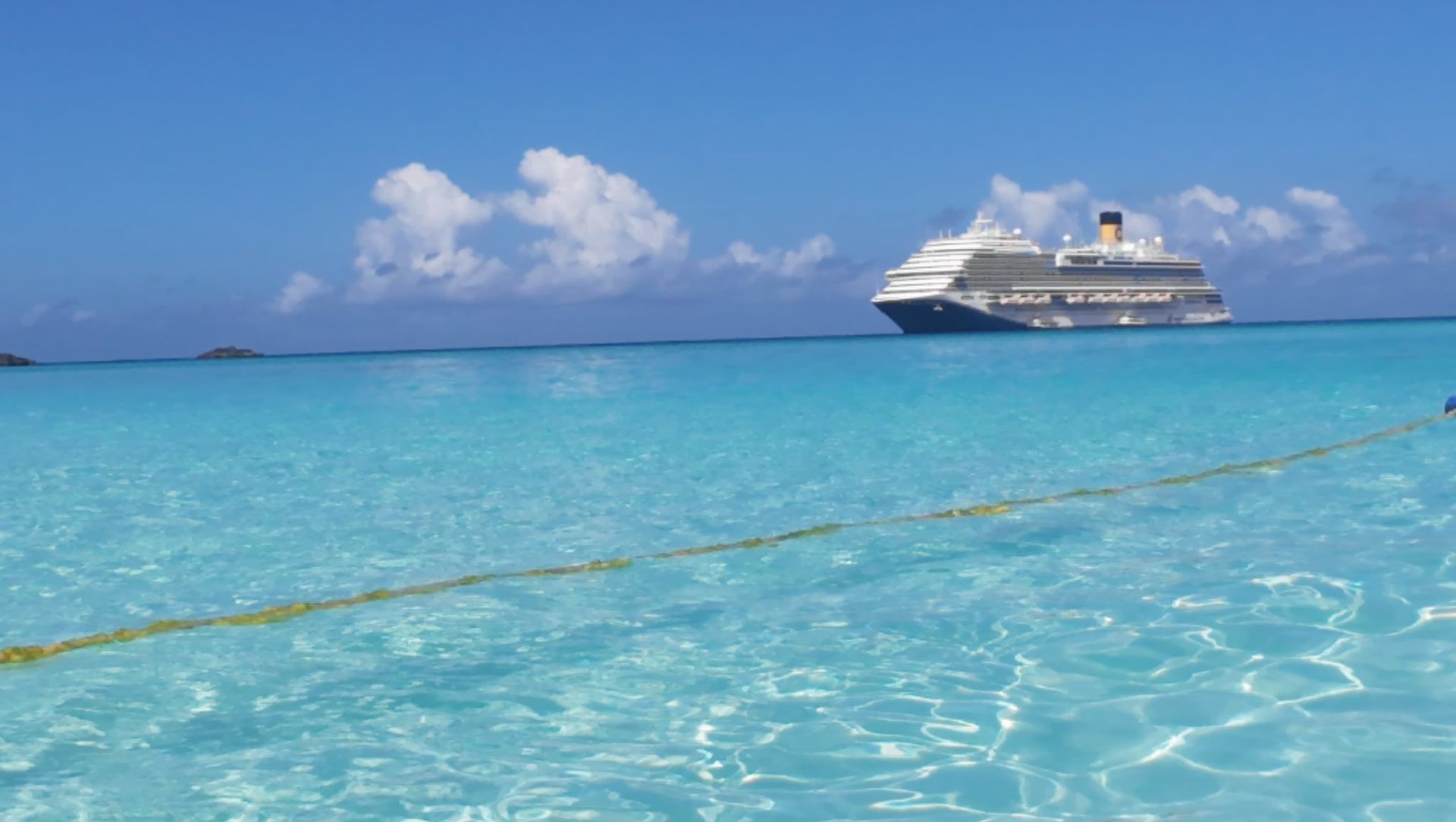 Cruise ship in turquoise water under a blue sky.