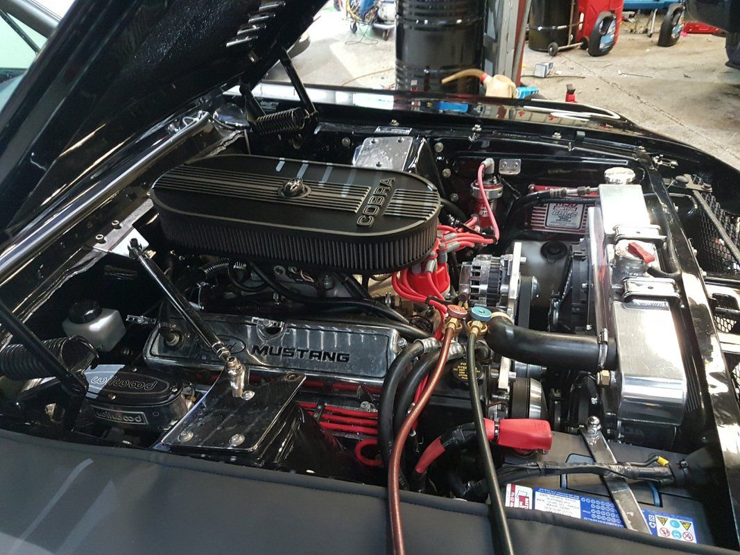 A close up of a car engine with the hood open