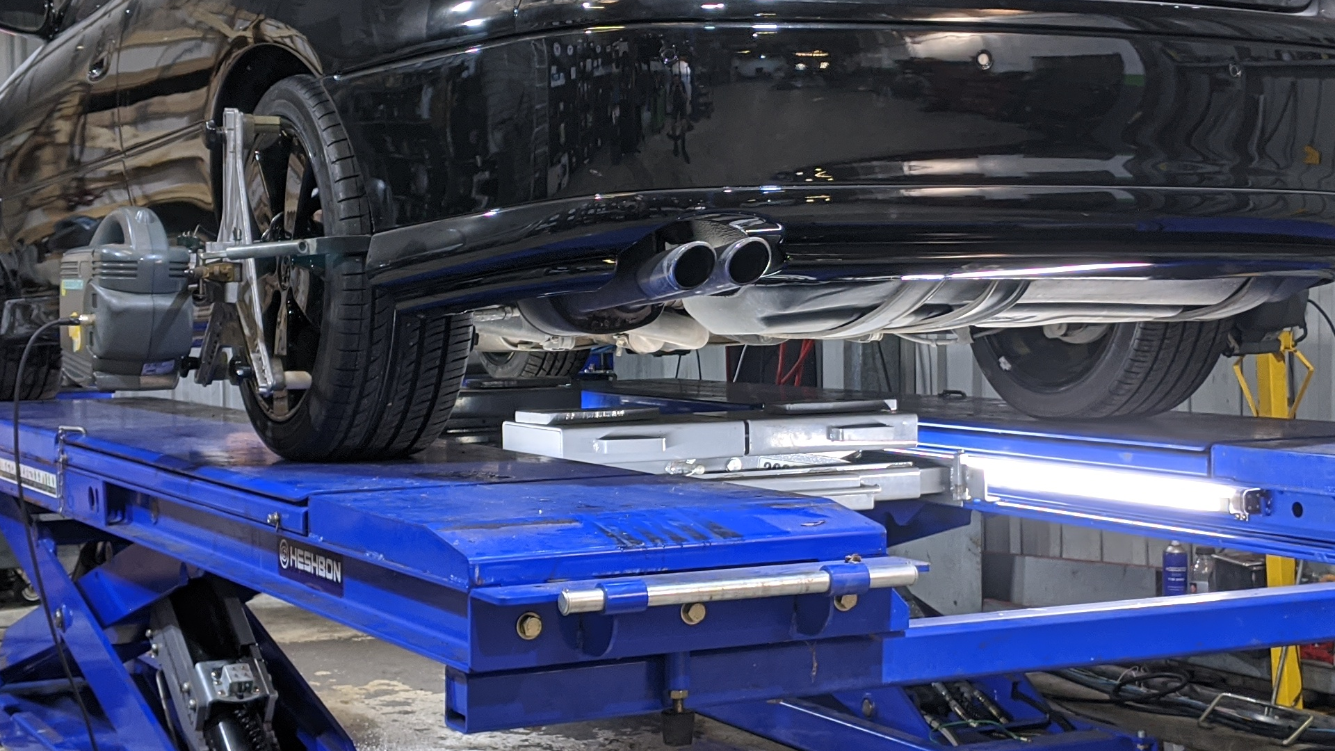A car is sitting on top of a blue lift in a garage.