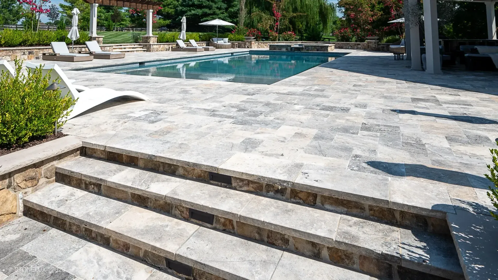 Luxury stone pool deck and patio, highlighting elegant hardscaping in Maryland.