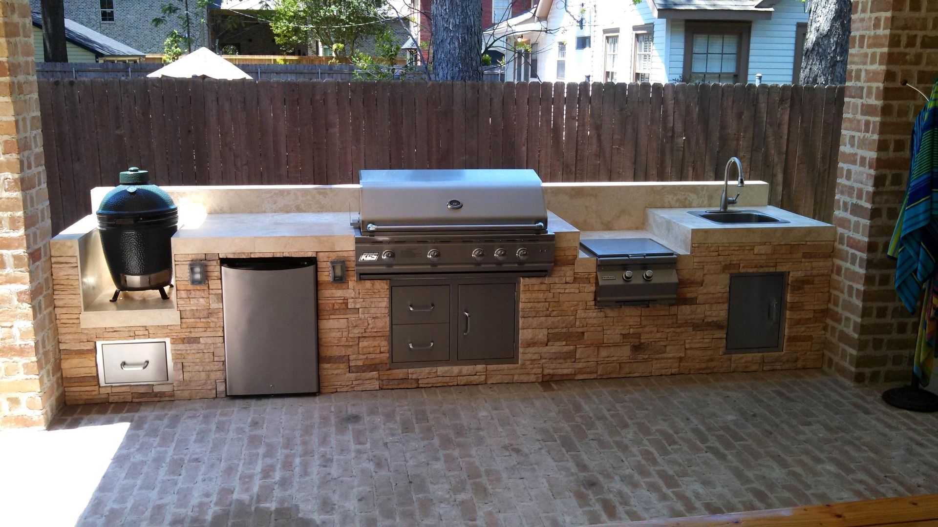 Fully equipped outdoor kitchen setup with grill, sink, and under-counter refrigerator
