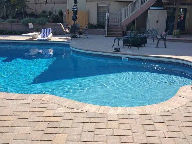 A large swimming pool with chairs and umbrellas around it