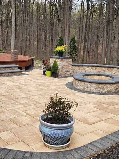 A potted plant is sitting on top of a patio next to a fire pit.