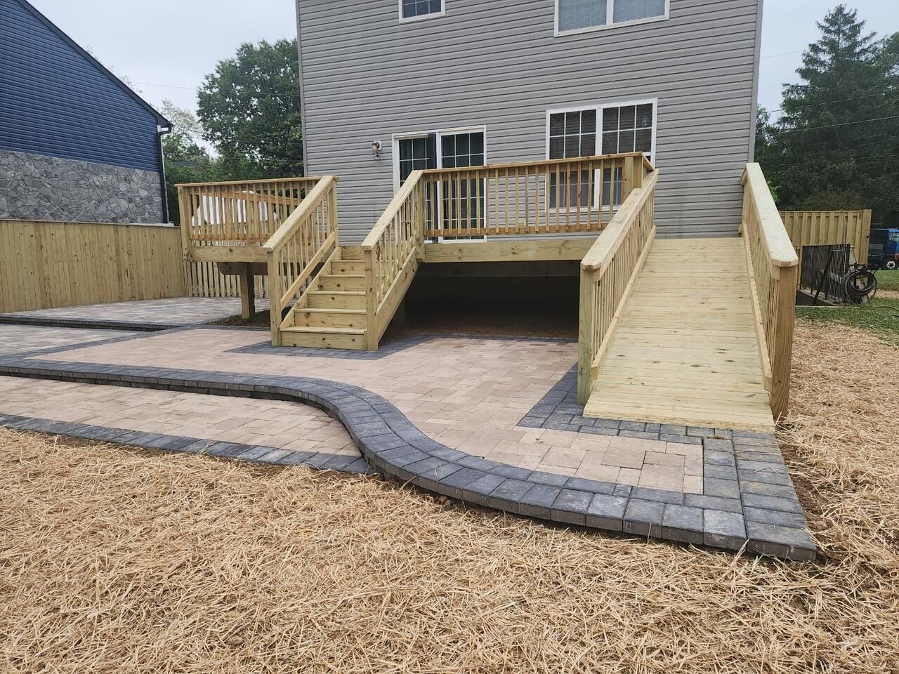 A wooden deck with stairs and a ramp in front of a house