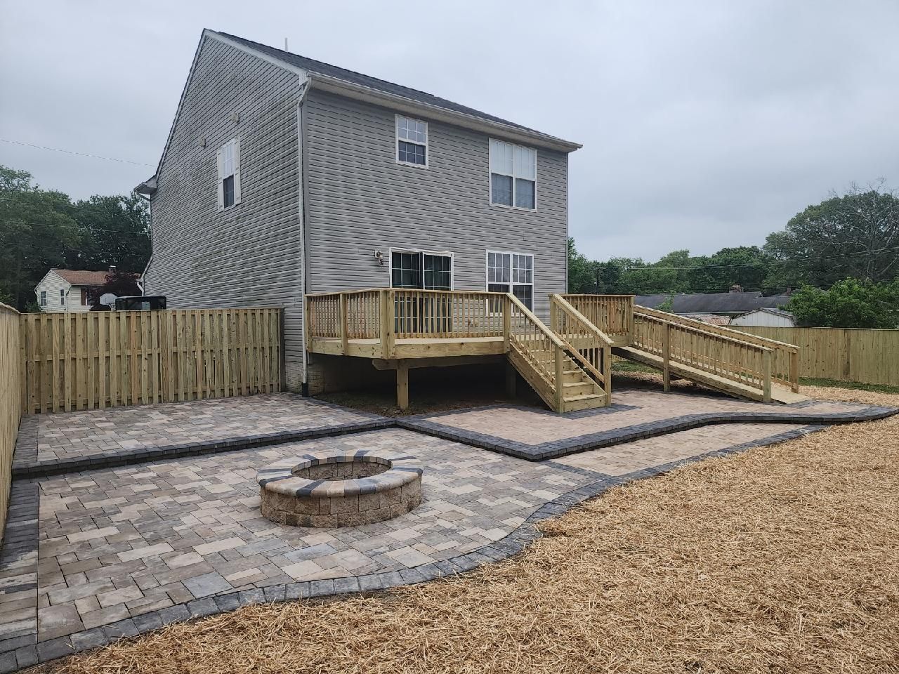 A house with a wooden deck and a fire pit in the backyard.