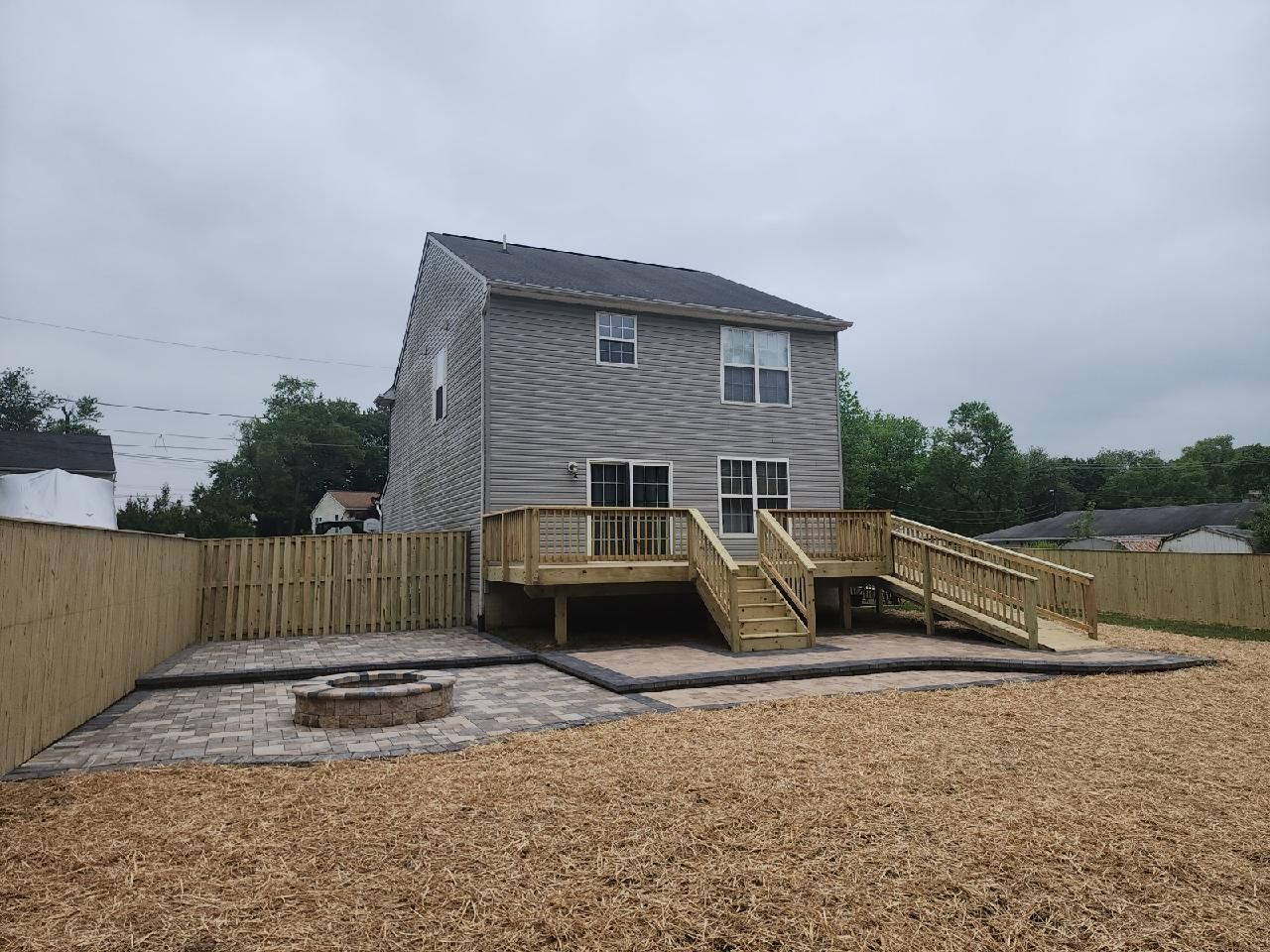 A house with a wooden deck and a fire pit in the backyard.