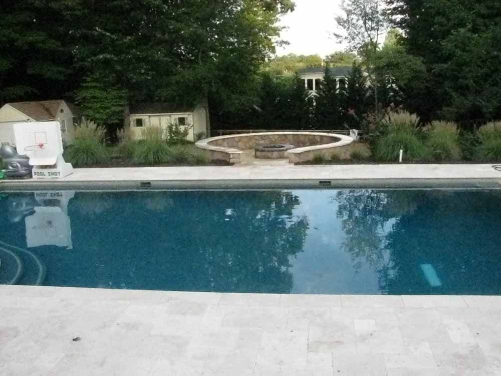 A large swimming pool with a fire pit in the backyard