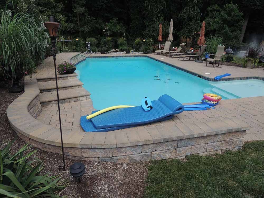 A large swimming pool with a blue raft on the edge of it.