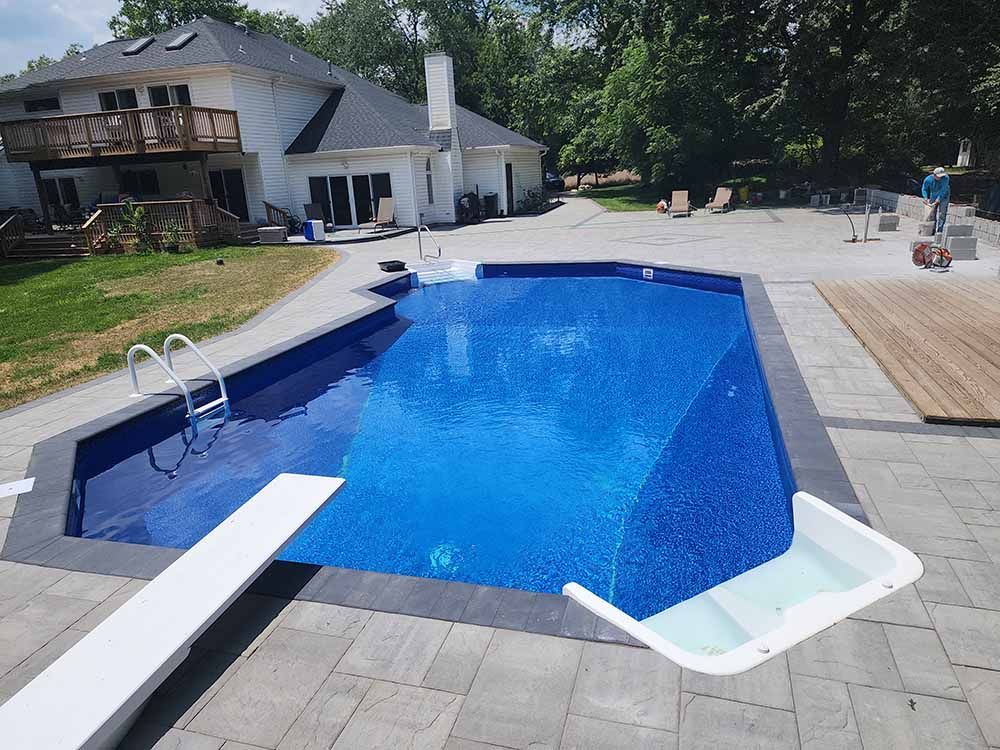 A large swimming pool with a diving board in front of a house