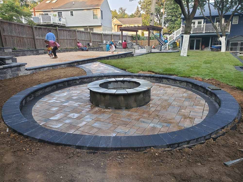 A fire pit is surrounded by a brick patio in a backyard in Maryland