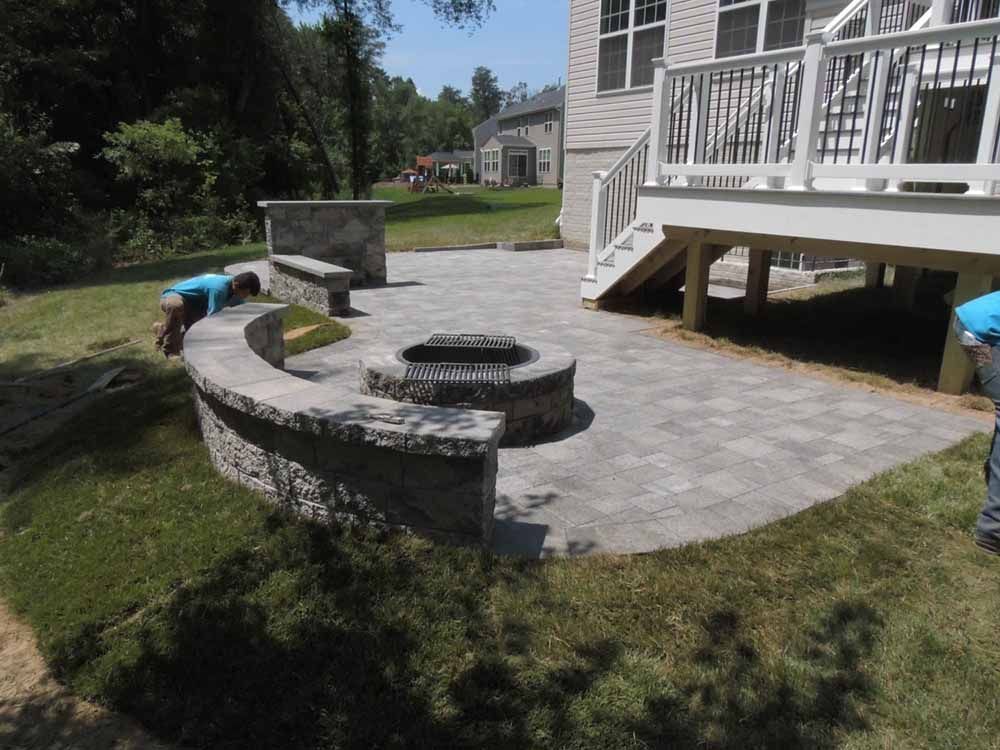 A man is working on a patio in front of a house