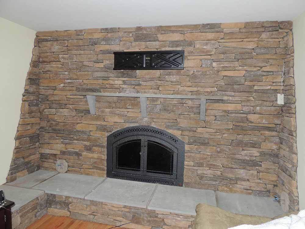 A living room with a fireplace and a stone wall