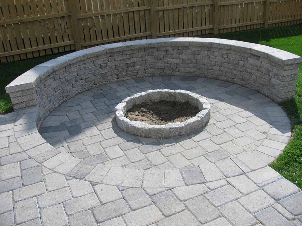 A fire pit is sitting in the middle of a brick patio.