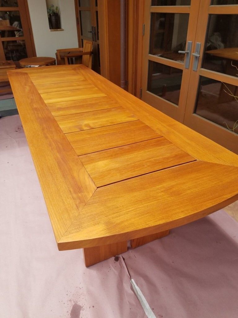 A long wooden table is sitting on top of a pink carpet in a room.