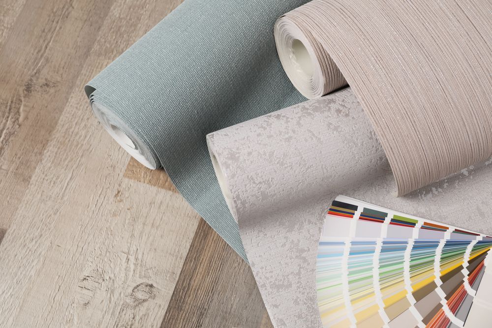 Rolls of wallpaper and a color palette on a wooden floor.