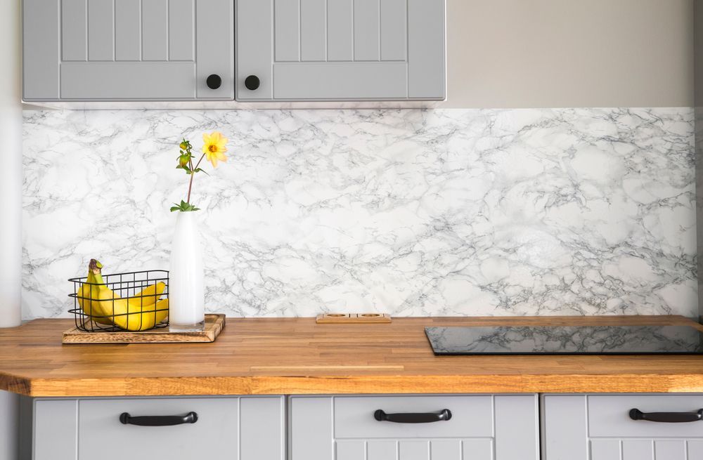 A kitchen counter with a basket of bananas and a vase of flowers.