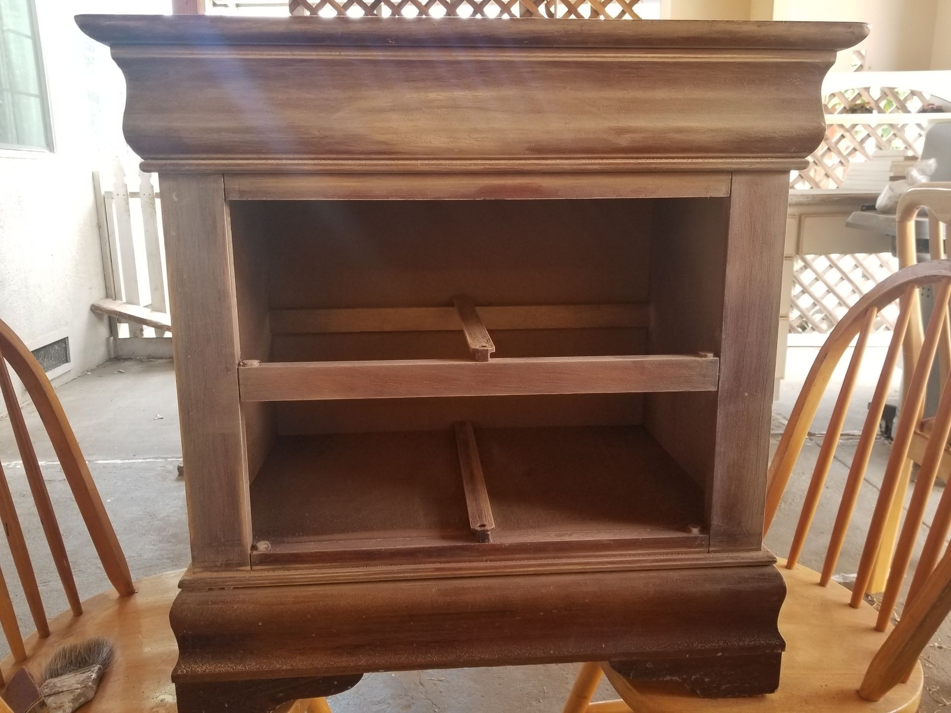 An empty wooden cabinet is sitting on a wooden chair