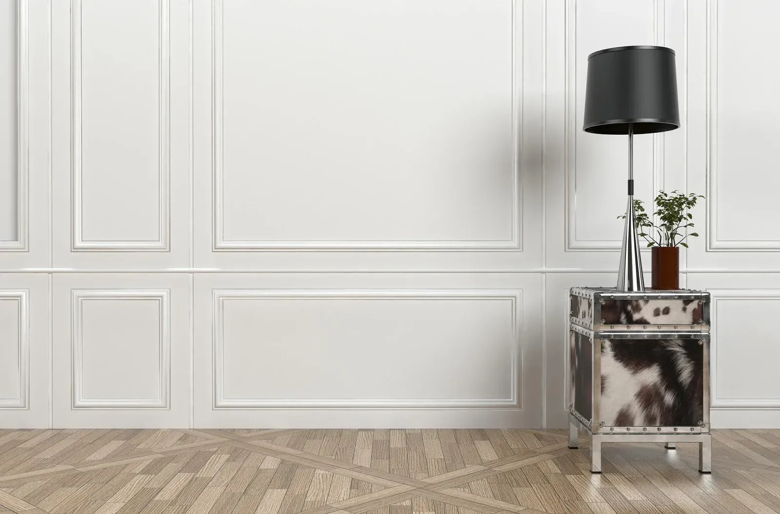 An empty room with a lamp and a nightstand in front of a white wall.