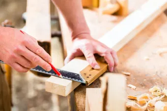 A person is measuring a piece of wood with a ruler.