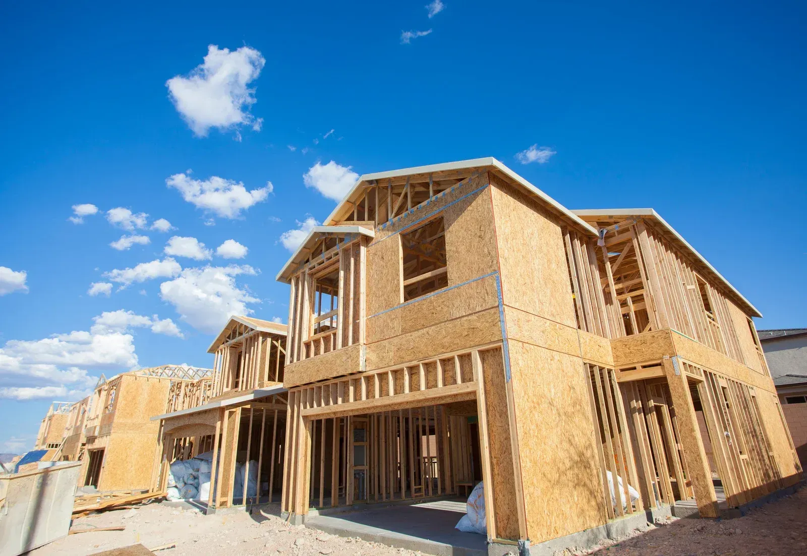 A large wooden house is being built with a blue sky in the background.