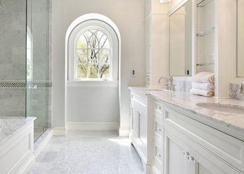 A bathroom with two sinks , a shower and a window.