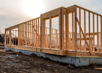 A wooden house is being built in a field.