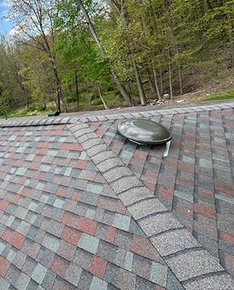 A roof with a skylight on it and trees in the background.