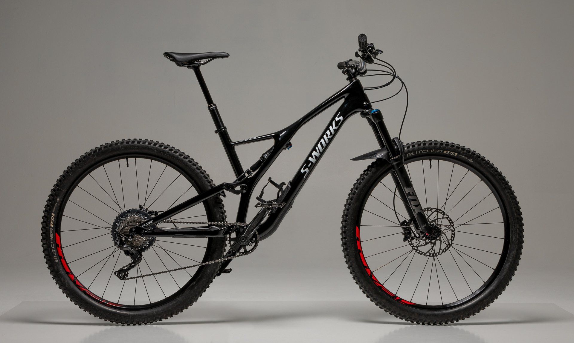 a black mountain bike is sitting on a white surface .