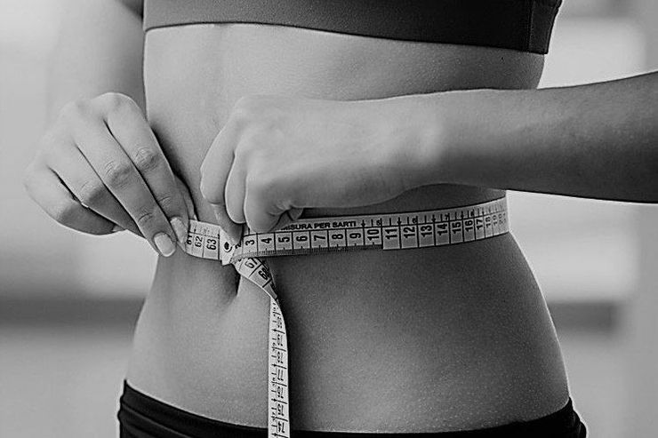 A shirtless man is standing on a balcony overlooking a city.