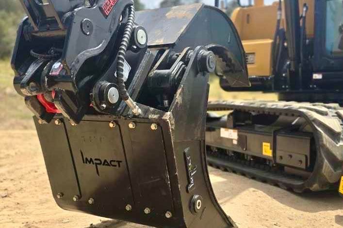 Black Impact grapple bucket attached to a yellow Caterpillar excavator.