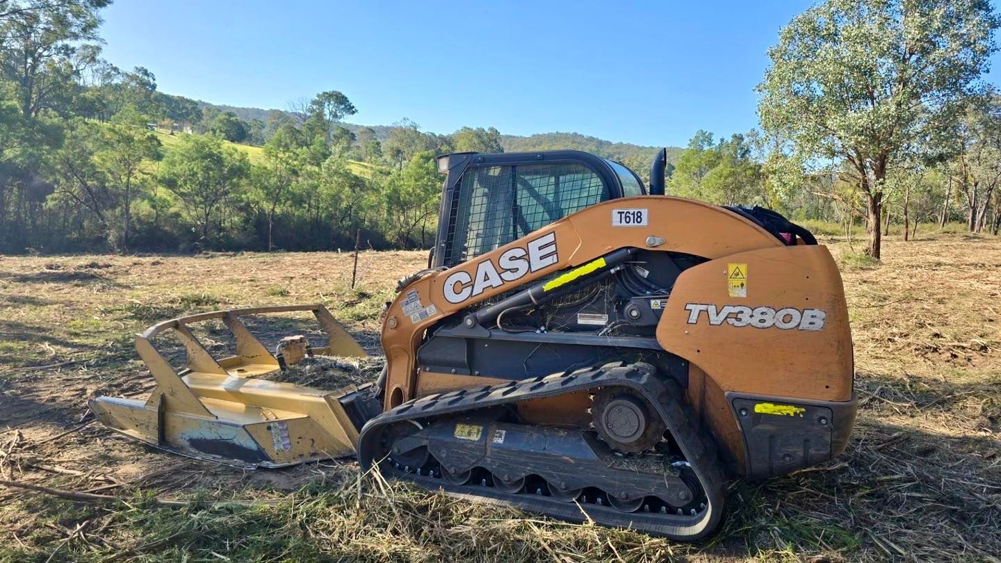 A Case TV380B compact track loader with a mulching head is clearing land on a sunny day.