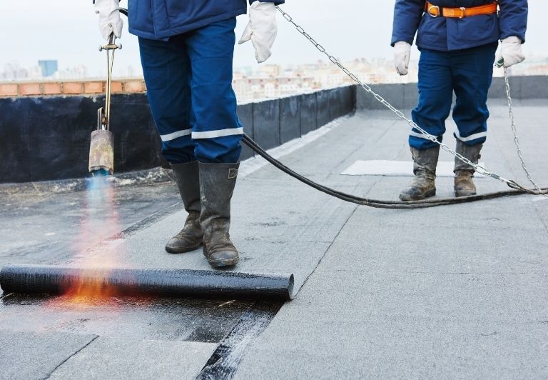 Black flat roof with vents and a blue sky in the background.