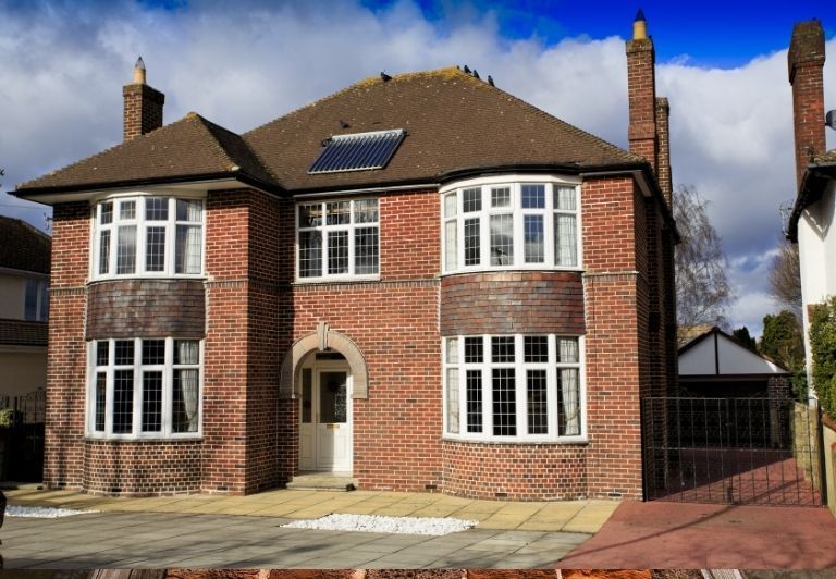 A person constructing a brick chimney on a roof. They are using a trowel-like tool.