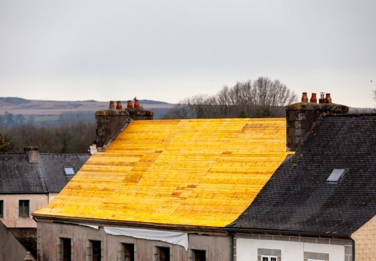 A metal roof with a skylight against a bright blue sky.