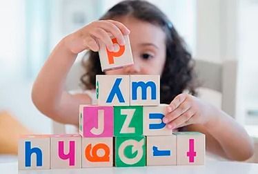 Niño apilando bloques de letras, concentrándose en la letra 