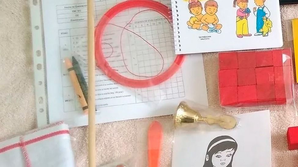 Juguetes infantiles variados y materiales de aprendizaje sobre una superficie de color claro, incluidos bloques, dibujos y un anillo.